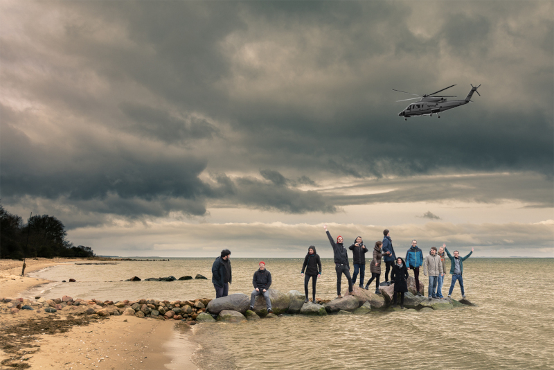 Das SynTAGit Team am Strand an der Nordsee. Darüber ein Helikopter